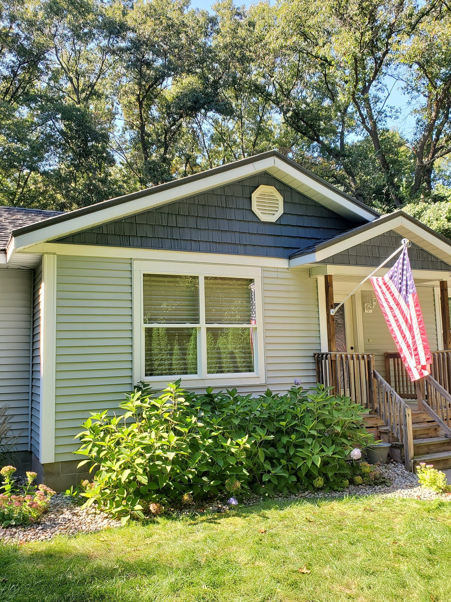 Small house exterior with blue siding, white trim, and an American flag on the porch.