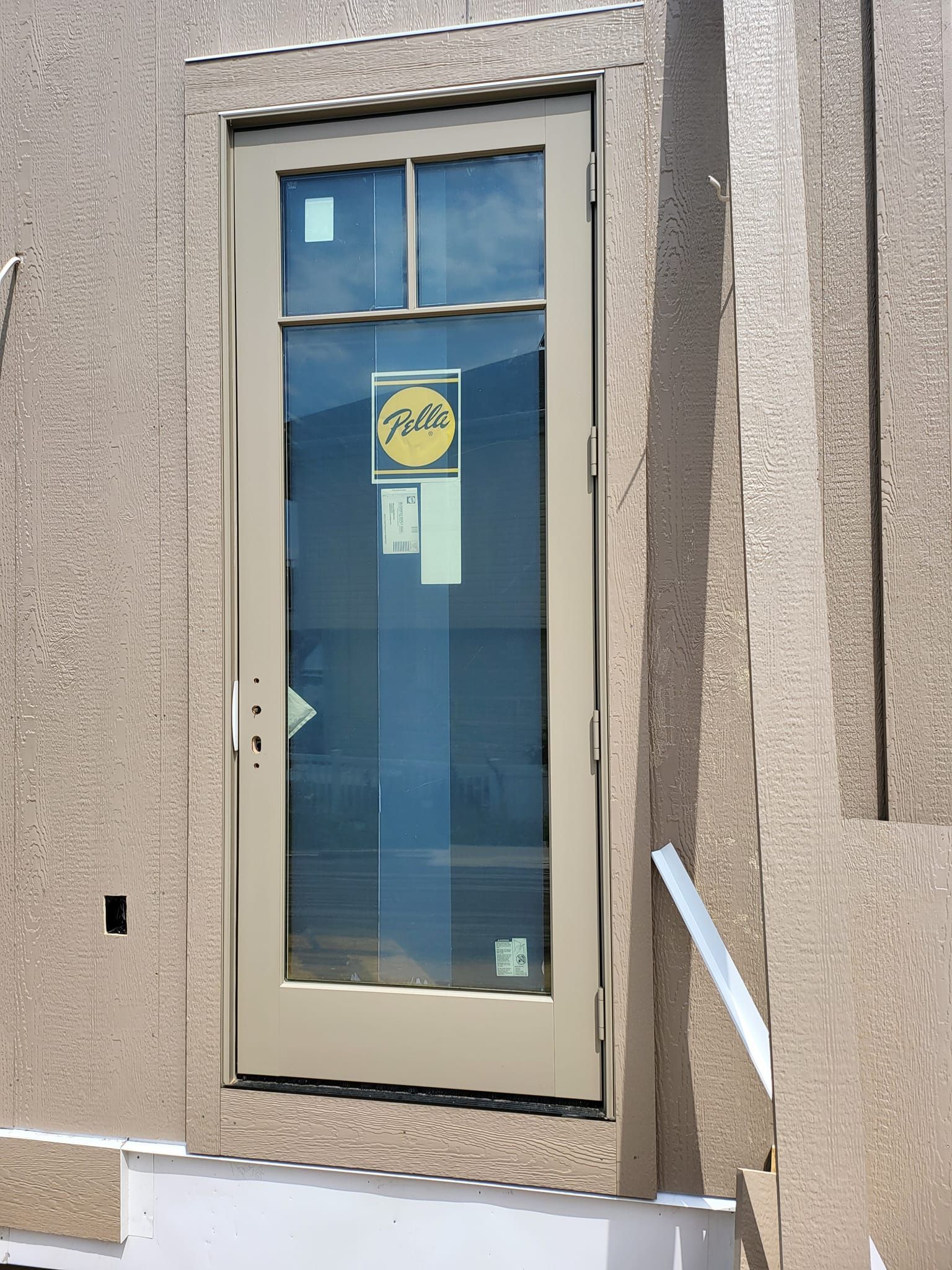 Closed beige door with a glass panel in a stucco wall, with a yellow sign inside the window.