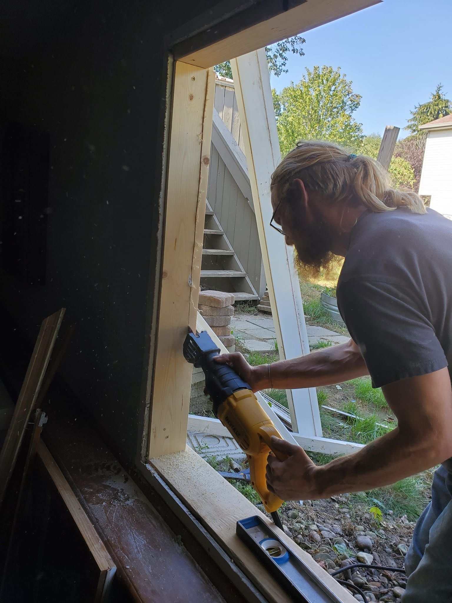 Person using a caulk gun to seal the edge of a window frame outdoors