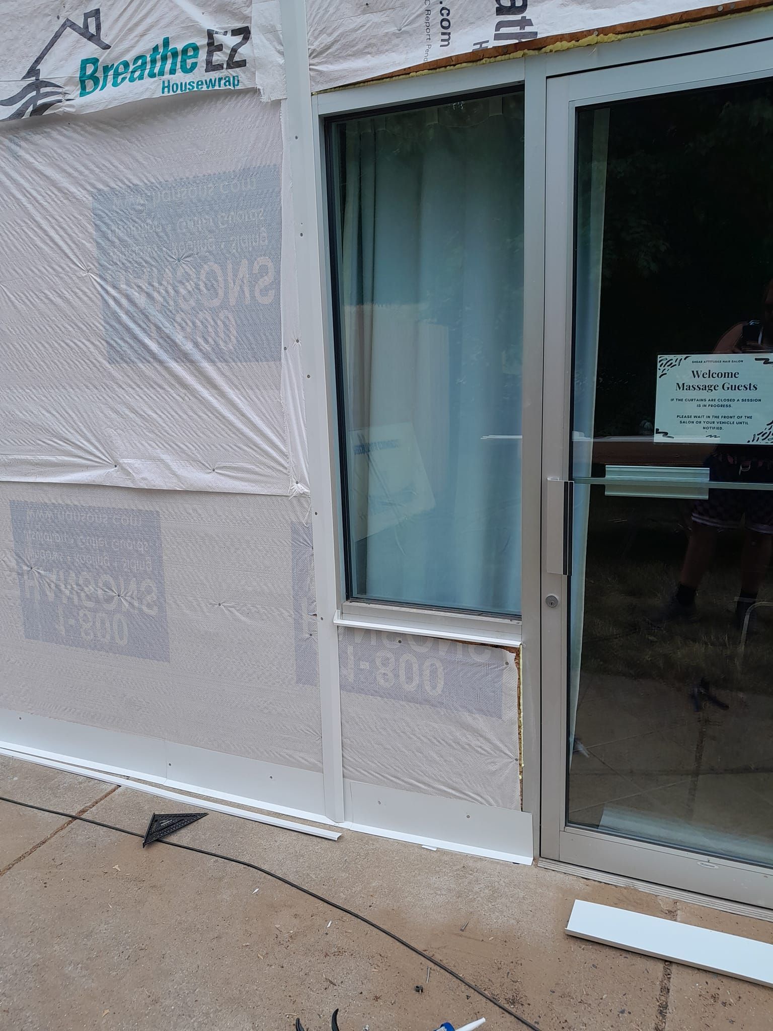Storefront with white mesh-covered windows and a glass door, seen from the sidewalk.