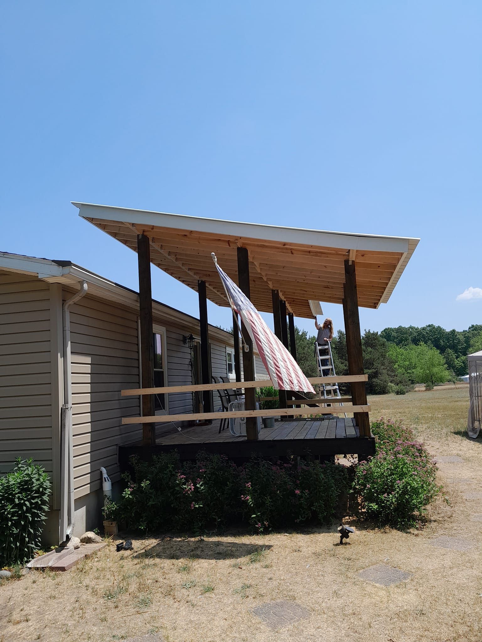 Small porch with a wooden roof and a hammock outside a beige house on a sunny day
