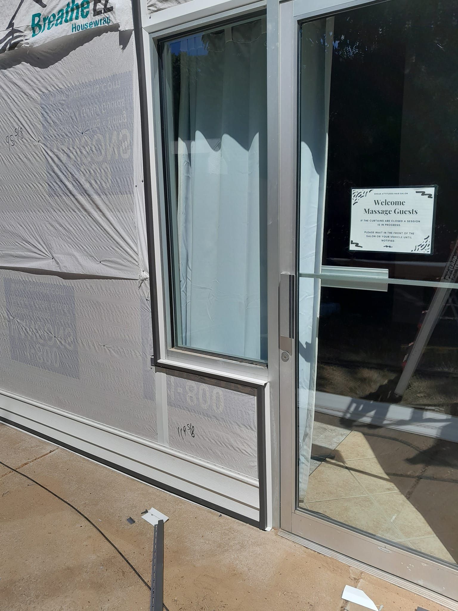 Storefront entrance with glass door, white trim, and a small sign on the window.