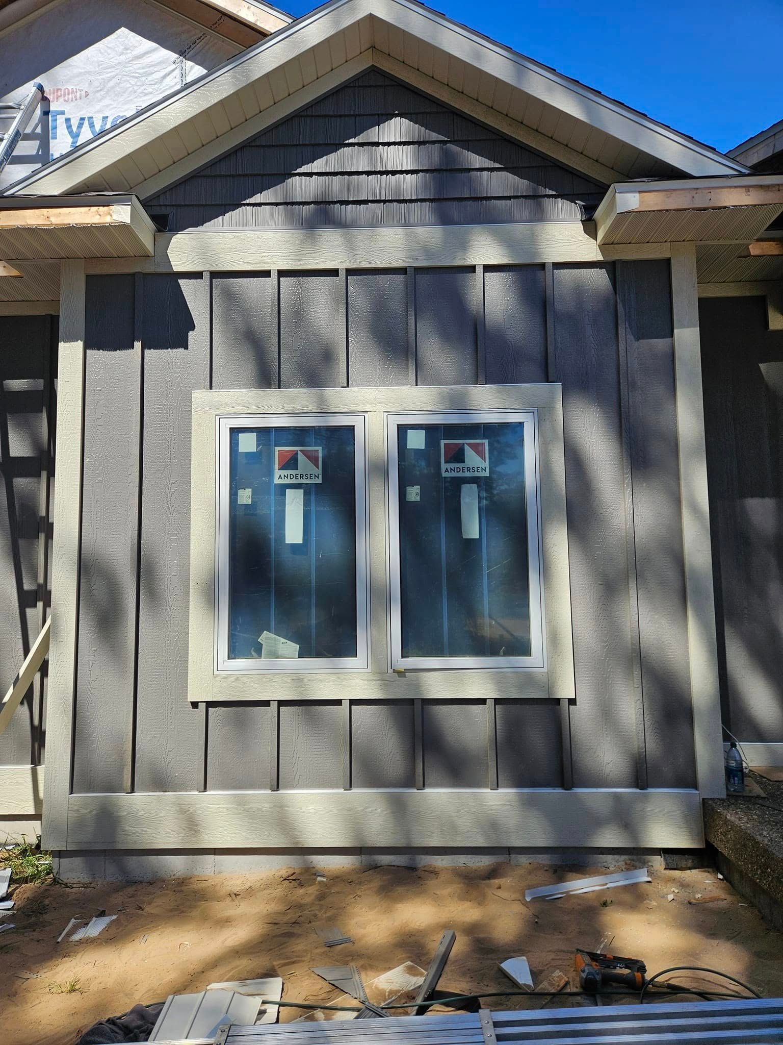 Gray-sided house exterior with two blue utility meter boxes beneath a gable roof.