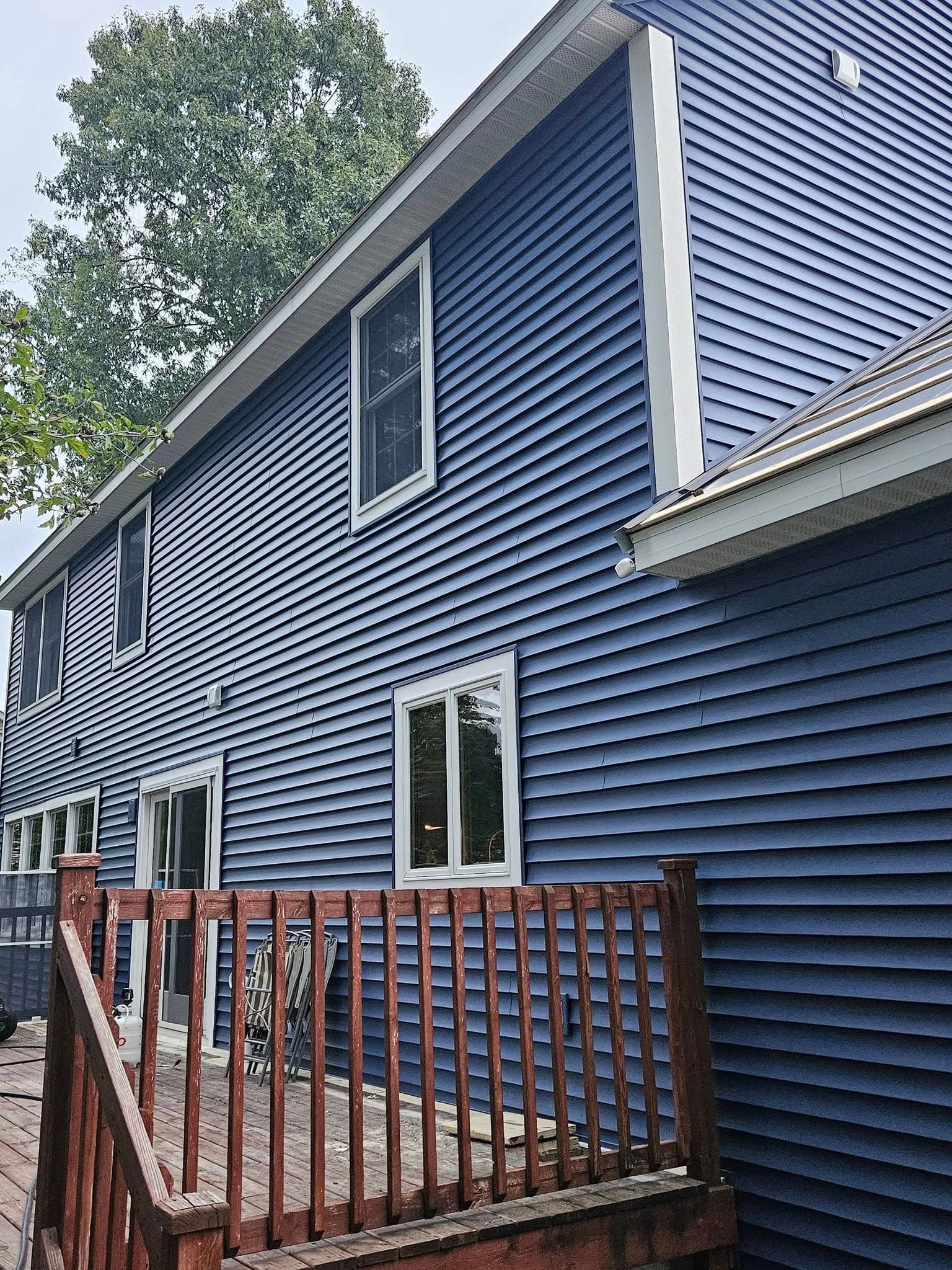 Blue-sided house with white trim and a red wooden deck fence