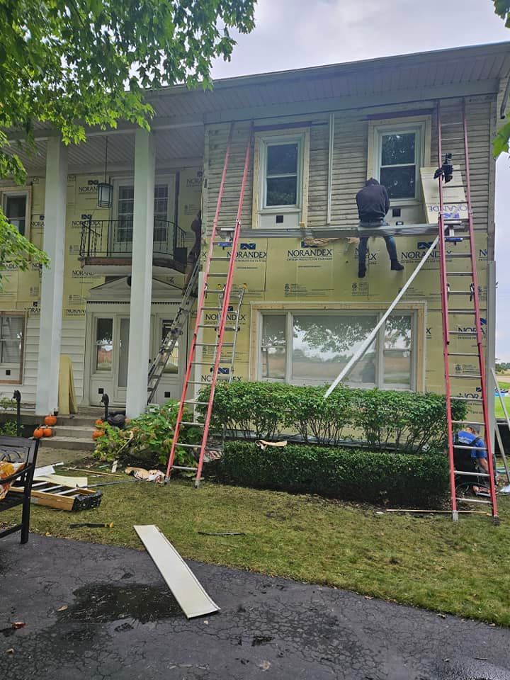 Workers on ladders repairing the exterior of a two-story house under construction or renovation