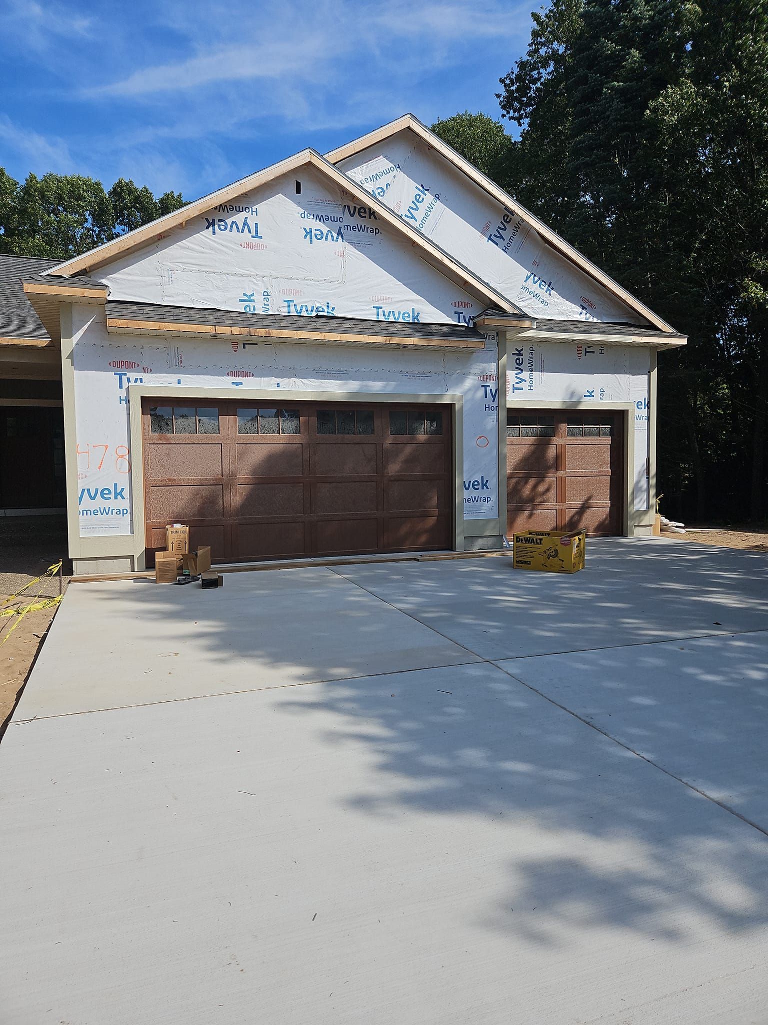 New house under construction with white siding, brown garage door, and a concrete driveway
