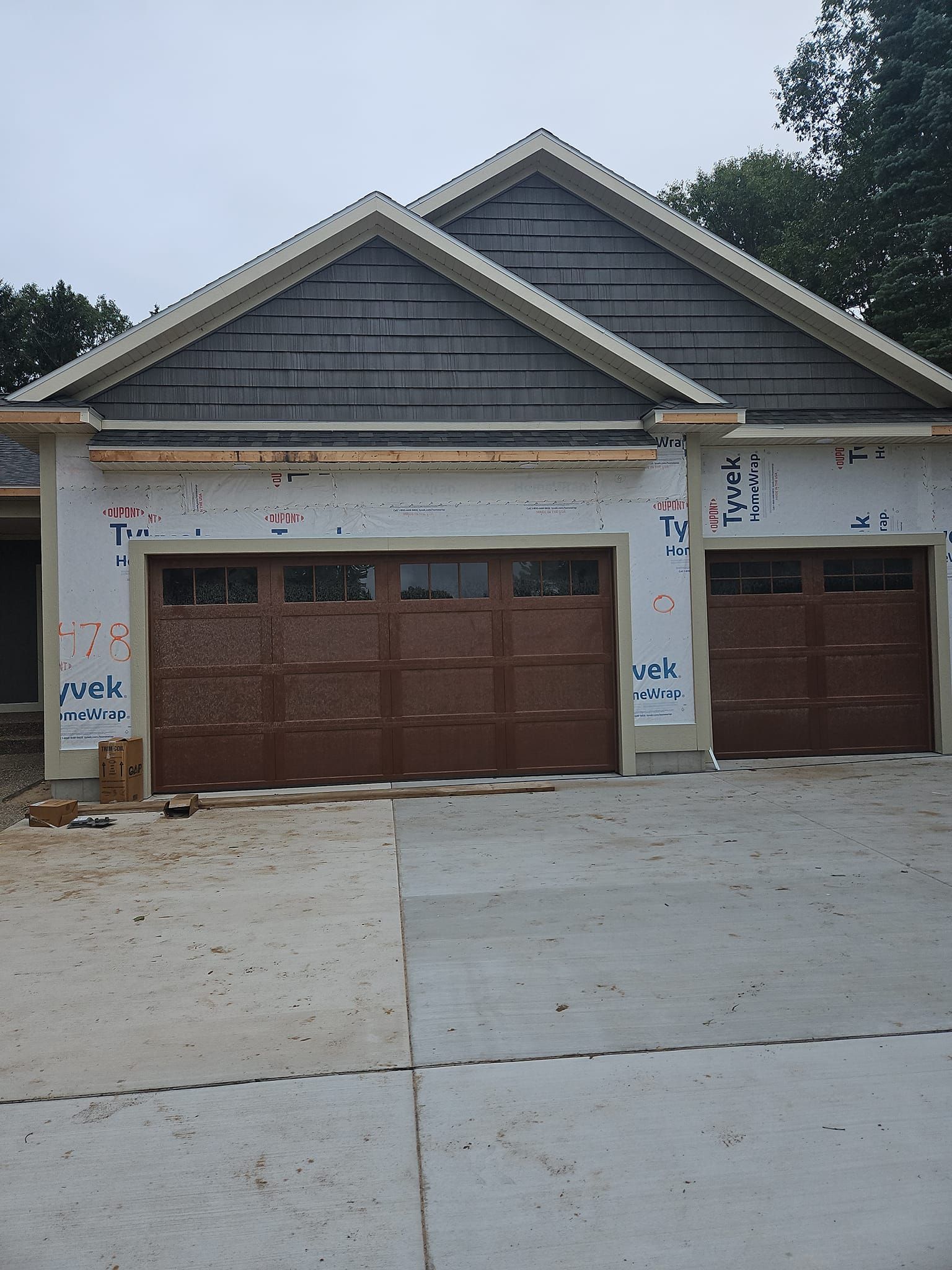 New suburban house with unfinished exterior and two brown garage doors