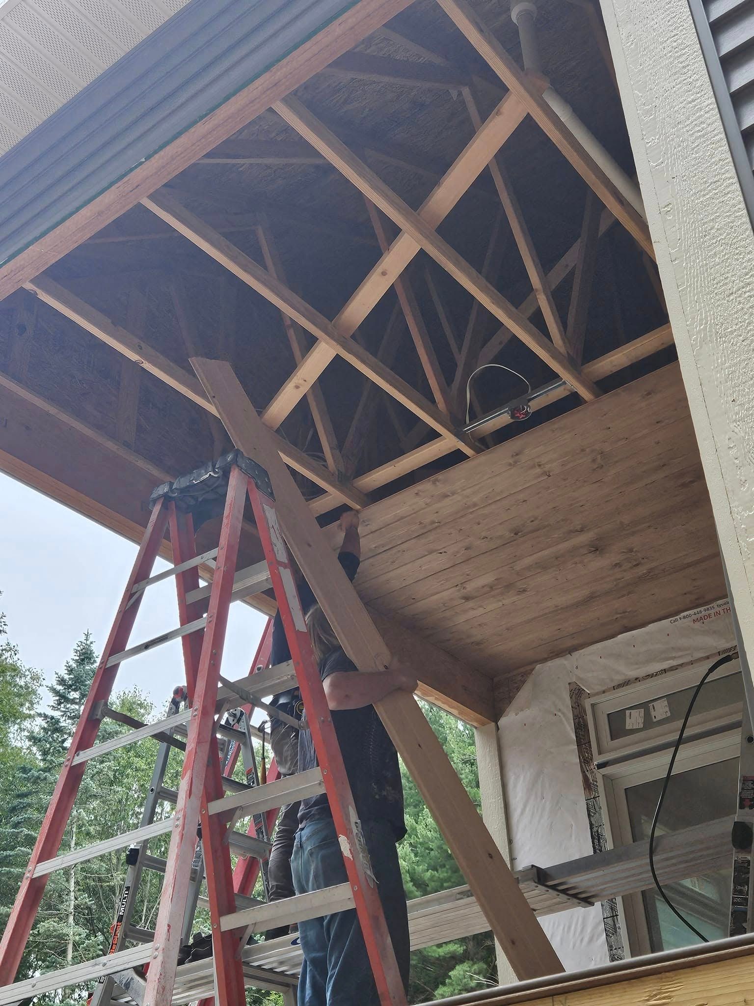 Ladder under an open roof, showing wooden trusses during home repair construction