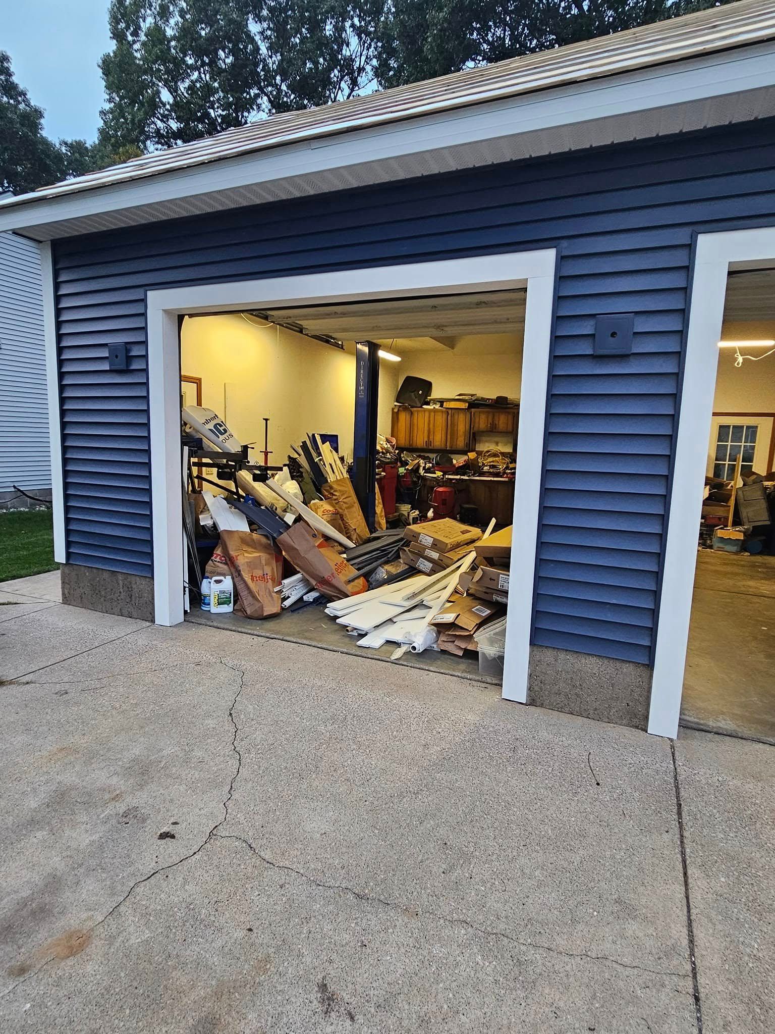 Blue garage with open door showing cluttered interior and scattered debris on the floor