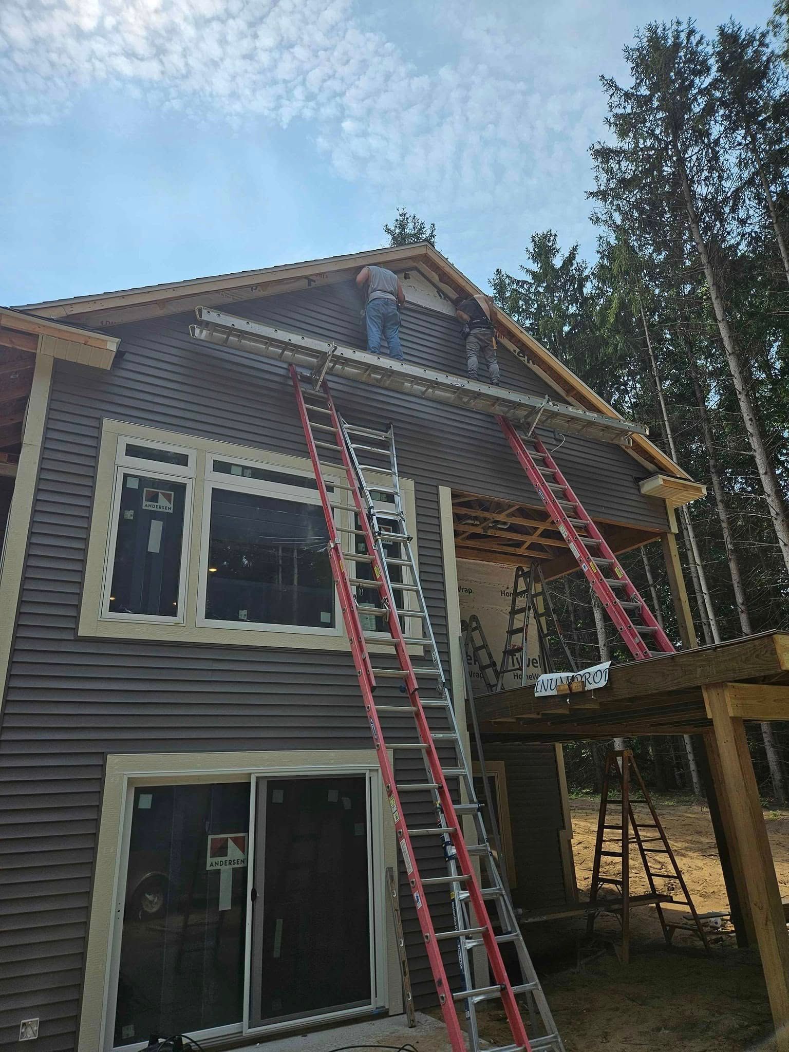 House exterior with two red ladders and rooftop scaffolding during repairs