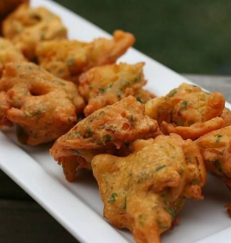 Golden-brown fritters arranged on a white rectangular platter, likely a savory appetizer.