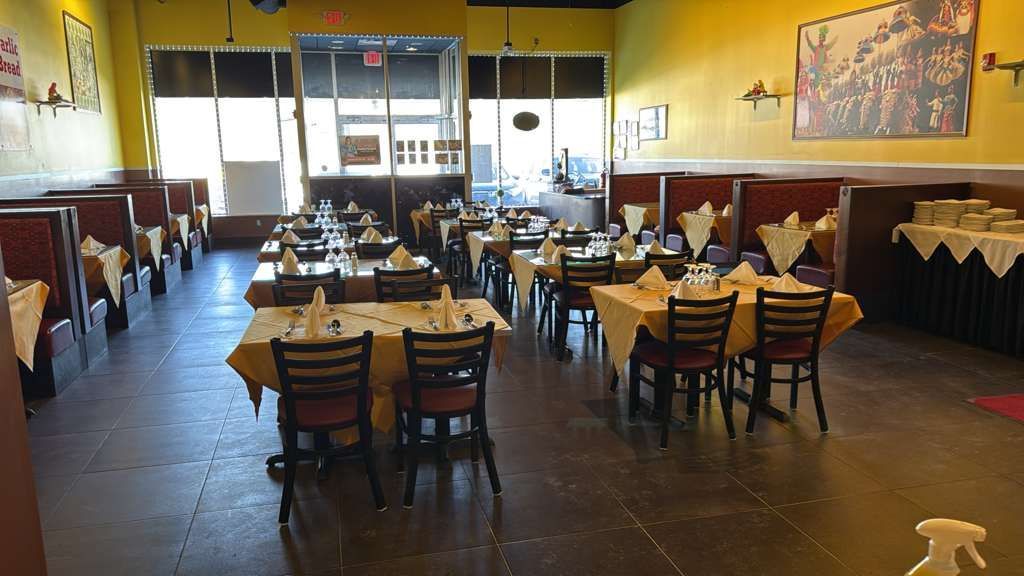 Restaurant interior: tables set with white tablecloths and chairs, yellow walls, and large windows.