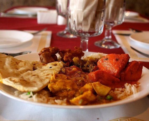 Plate of Indian food: naan, rice, curries, and tandoori chicken, served in a restaurant.