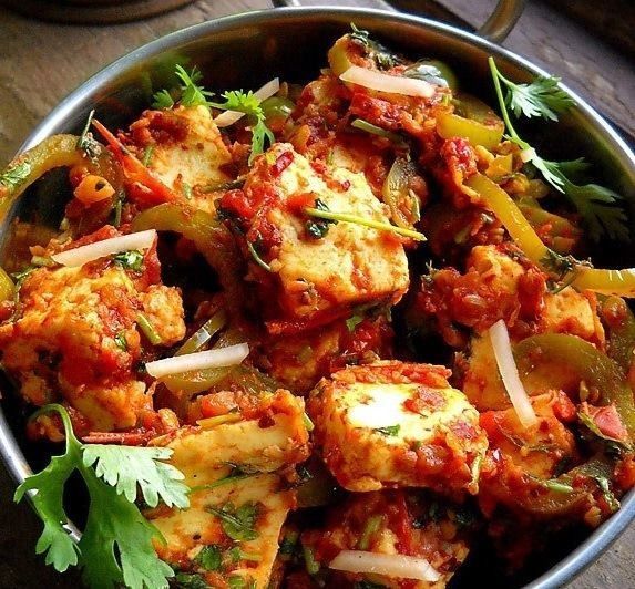 Paneer tikka masala in a metal bowl, with peppers, onions, and cilantro.