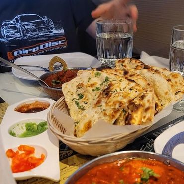 A table with Indian food: naan bread, curries, and dipping sauces.