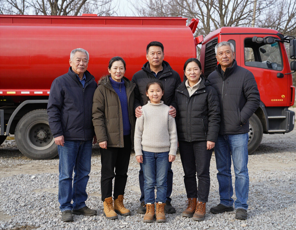 Family standing in front of a red septic truck