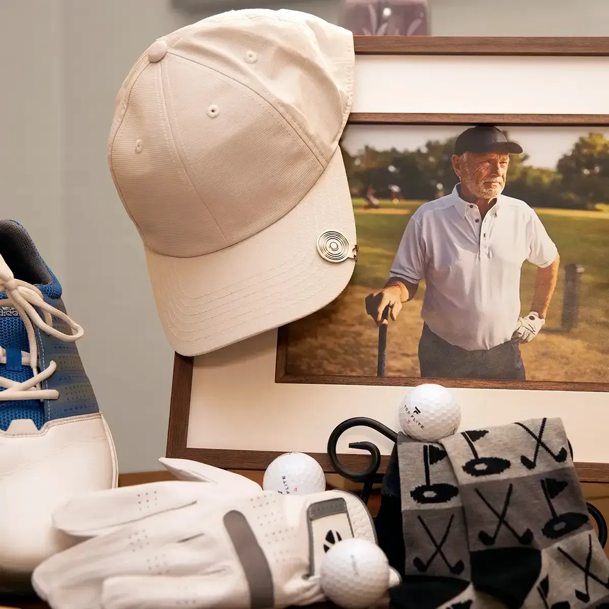 Memorial display with portrait beside a beige cap, golf shoes, white glove, and golf balls