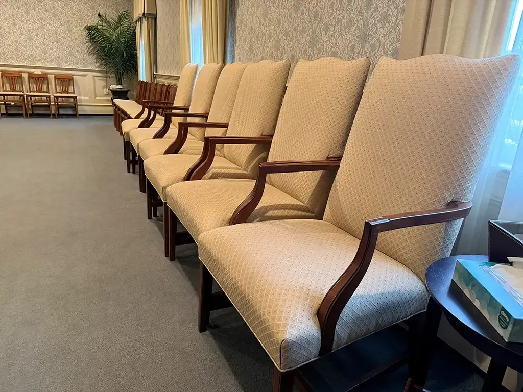 Row of beige upholstered chairs with wooden arms in a lounge area