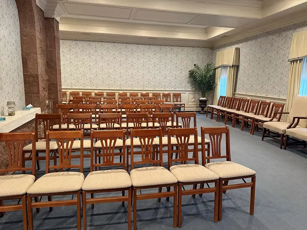 Empty chapel with rows of wooden chairs and benches facing the front.