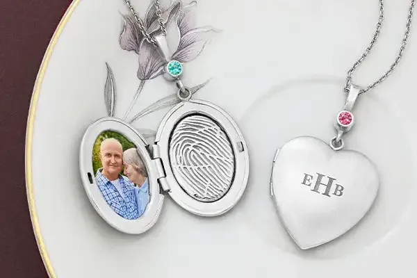Silver locket necklace with a small portrait and engraved heart pendant reading “EHB”
