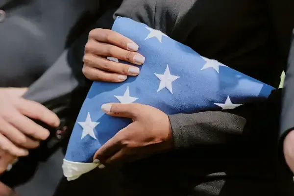 Hands holding a folded American flag during a solemn ceremony