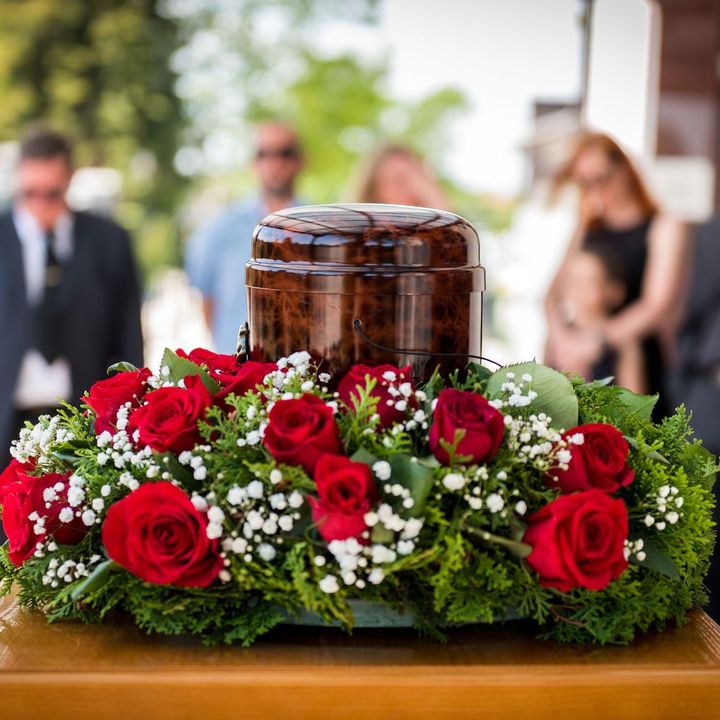 Cremation urn surrounded by red roses at a funeral viewing