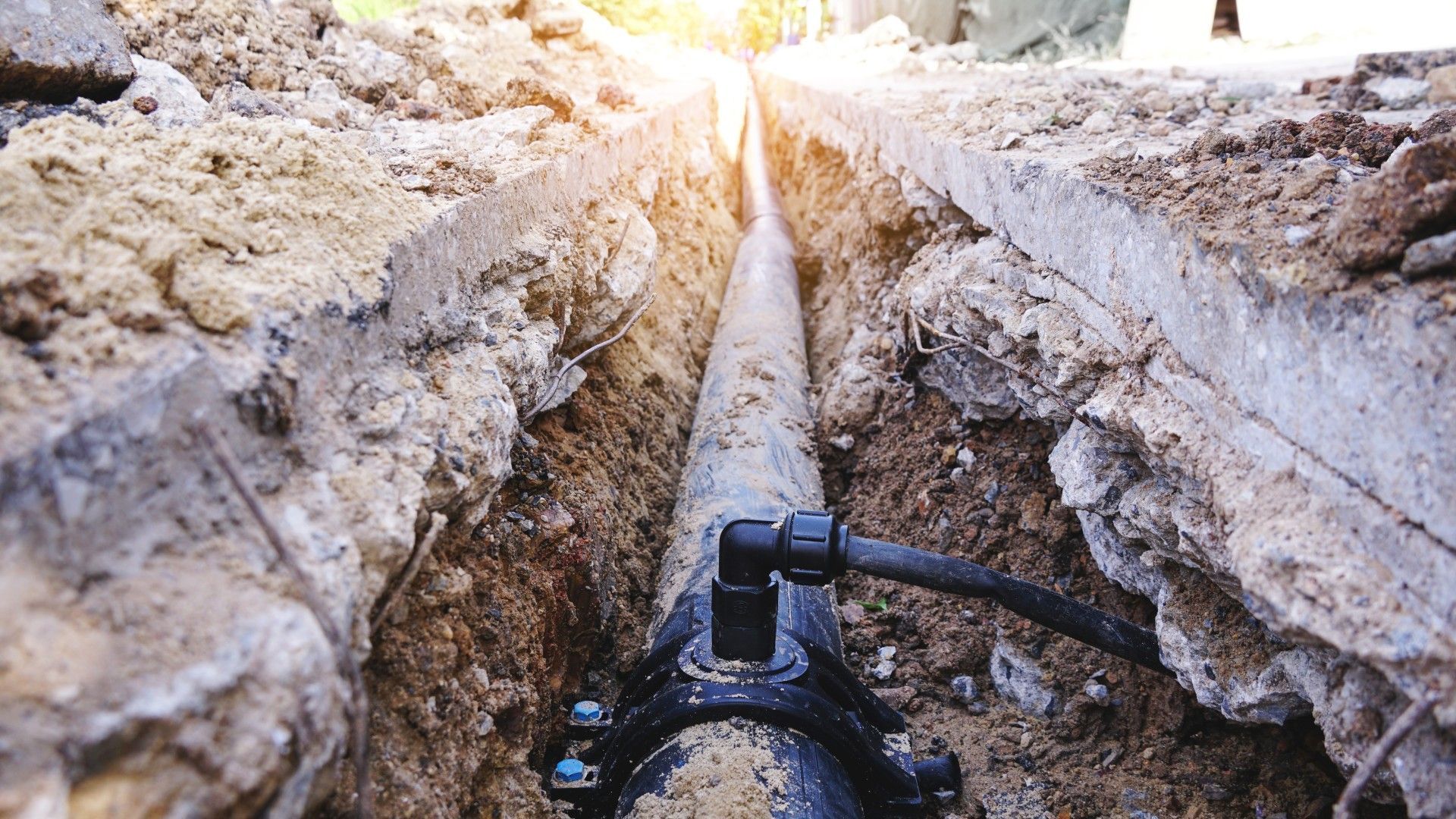 A pipe is being installed in the ground in a trench.