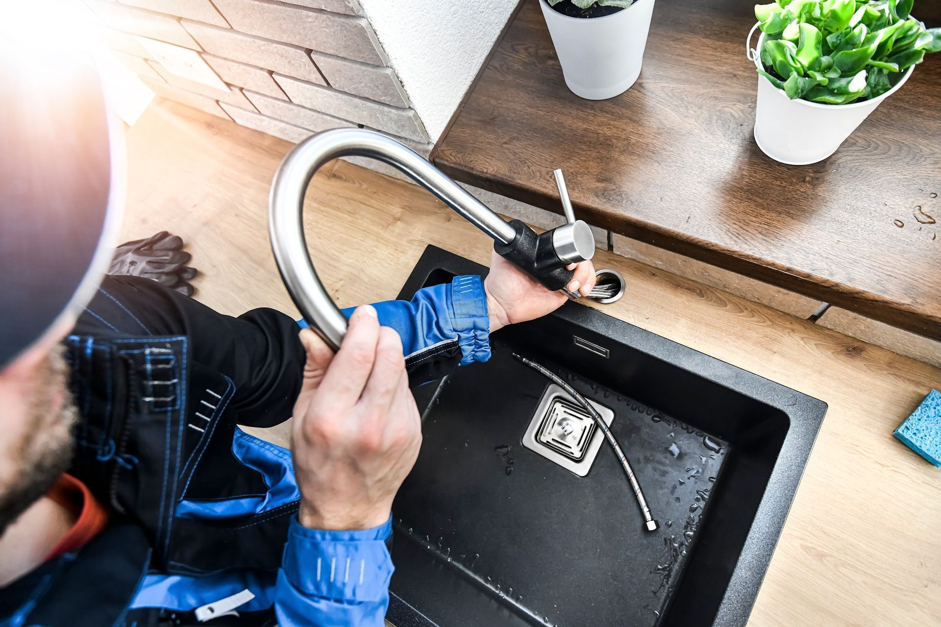 A man is fixing a faucet in a kitchen sink.