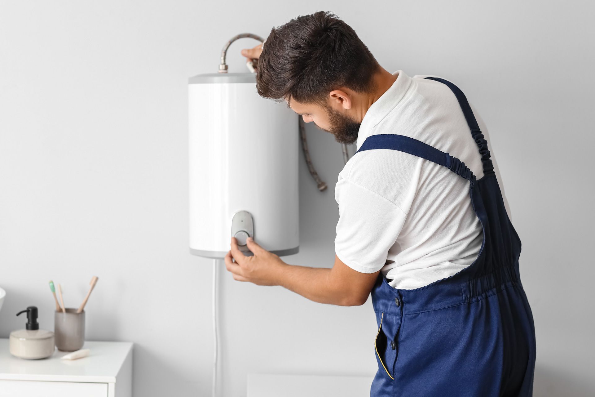 A man is installing a water heater in a bathroom.