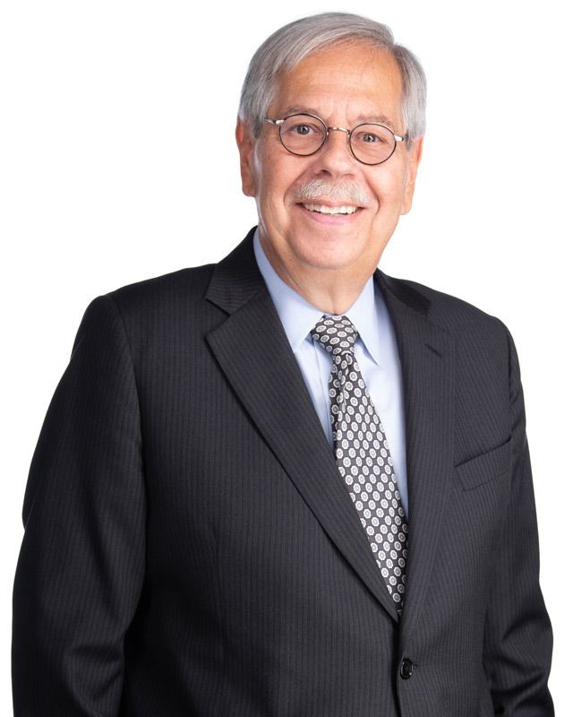 A man in a suit and tie is smiling for the camera