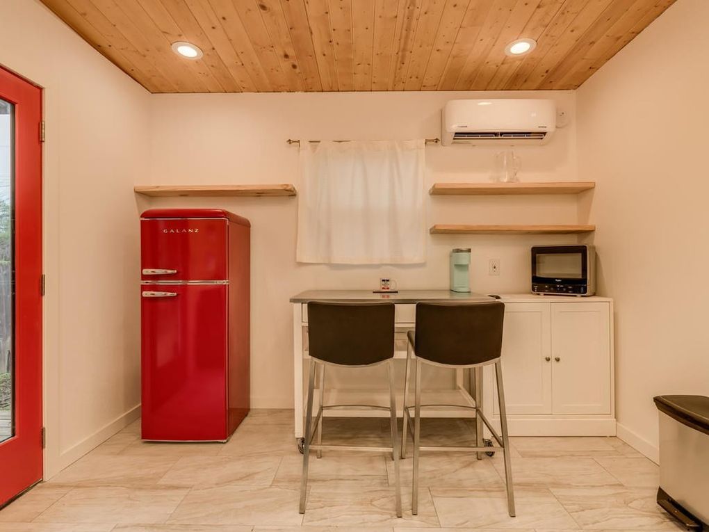 Small kitchen with red refrigerator, small table with two chairs, and white cabinets.