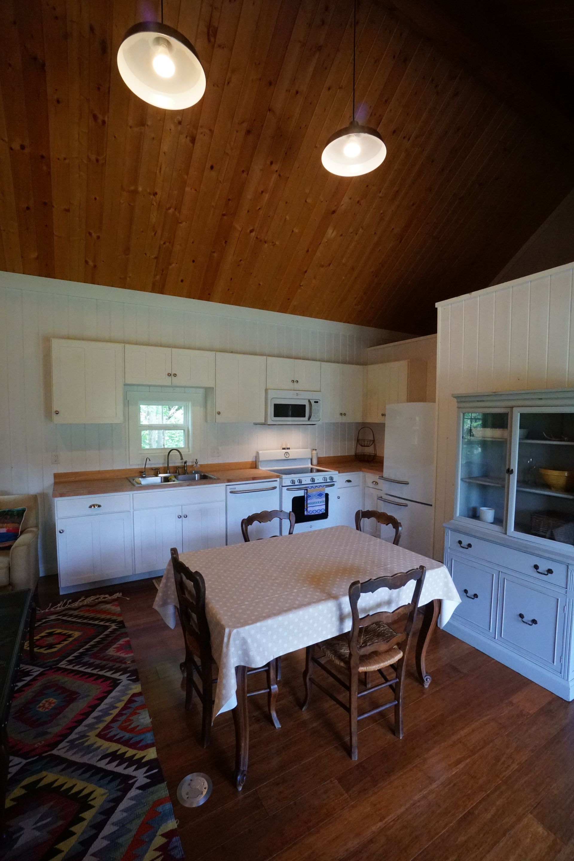 Kitchen with white cabinets, wooden ceiling, and dining table.