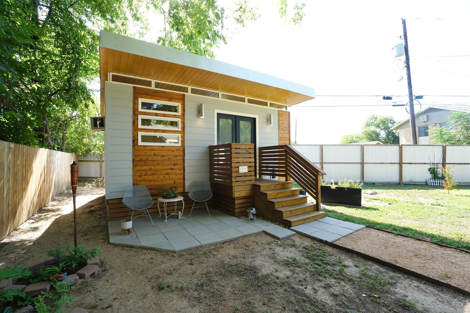 A small house with a patio and stairs in the backyard.