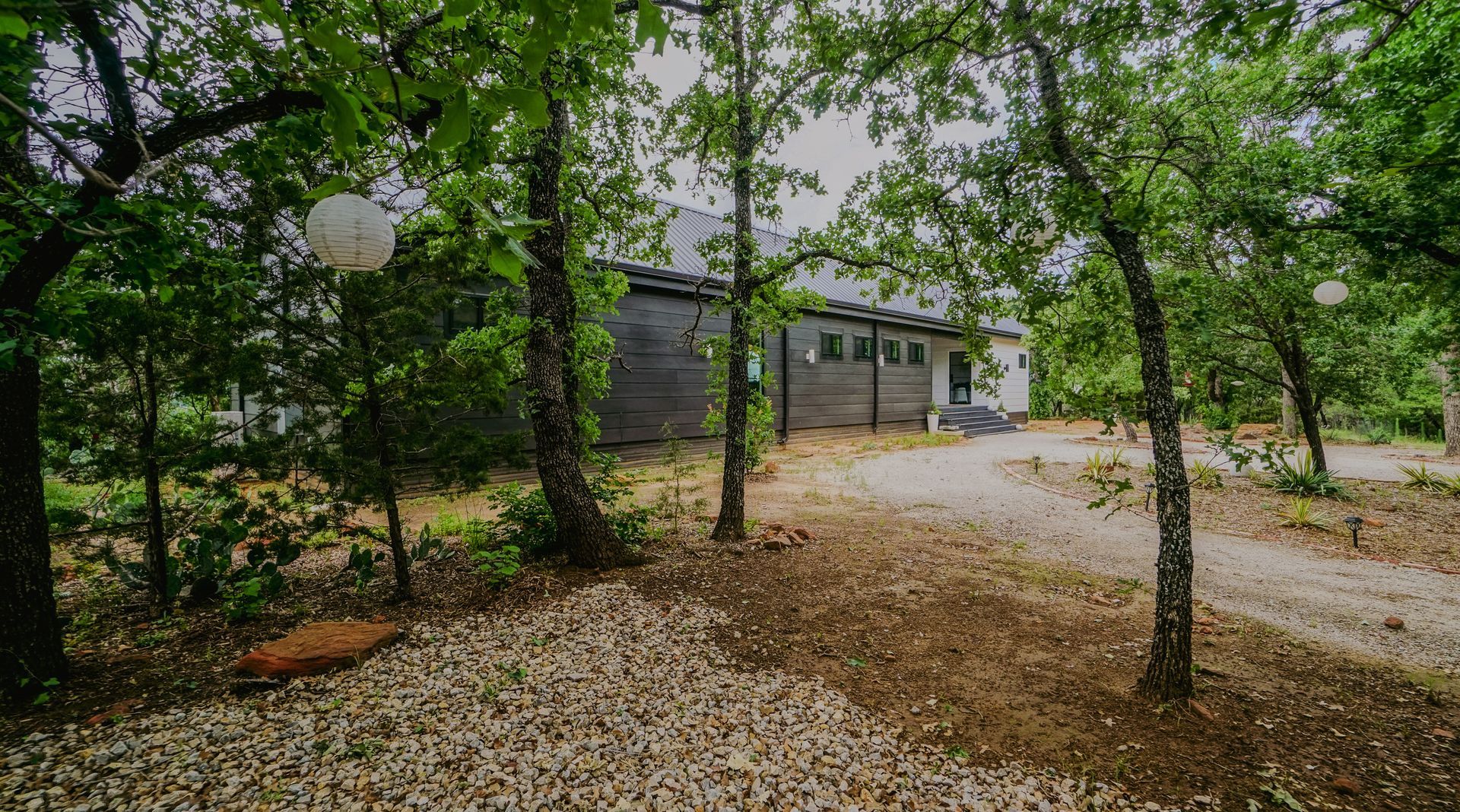 A gravel path leads to a wooden building nestled among trees.