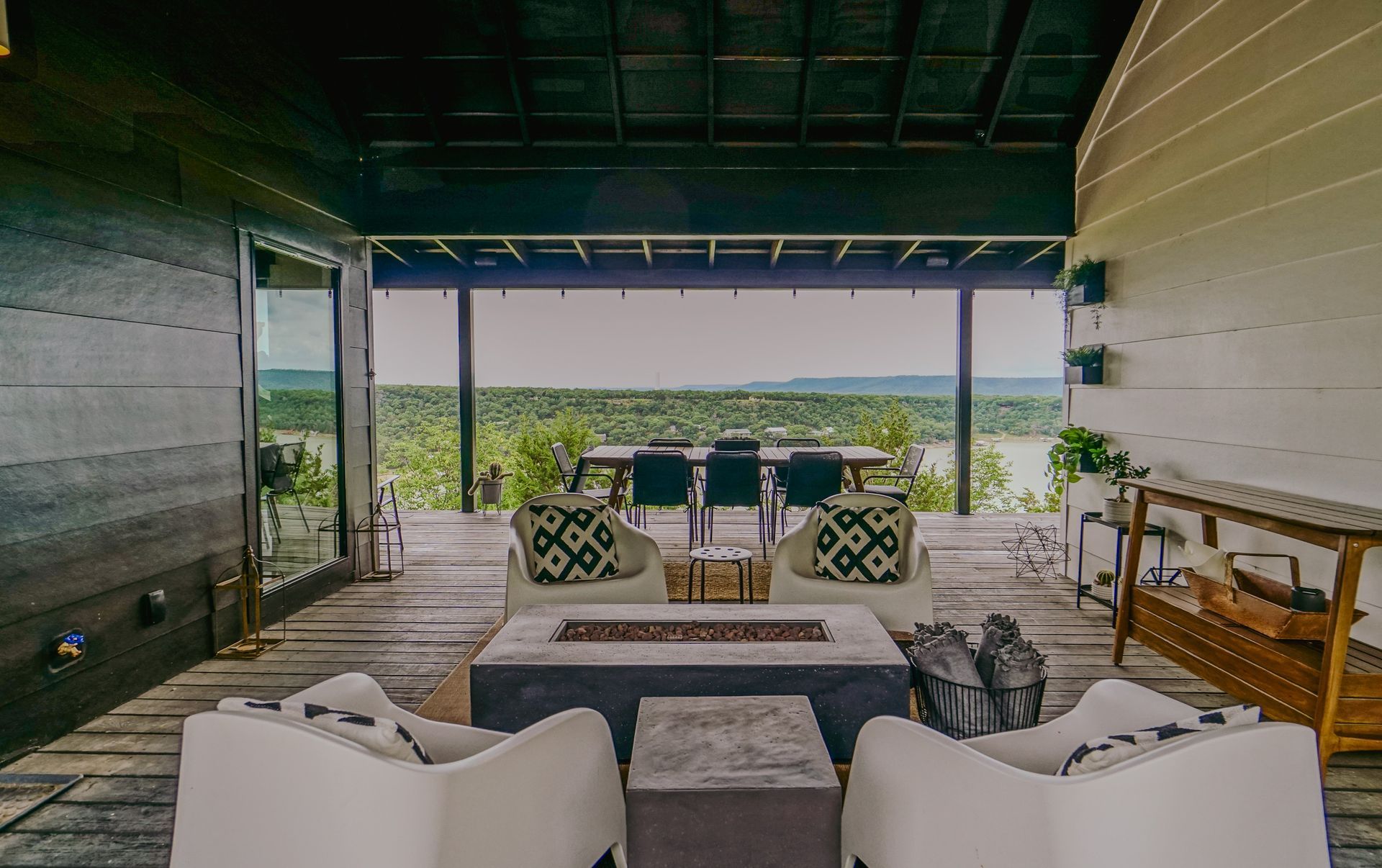 Outdoor seating area with a view; two white chairs around a fire pit, dining table in the distance.