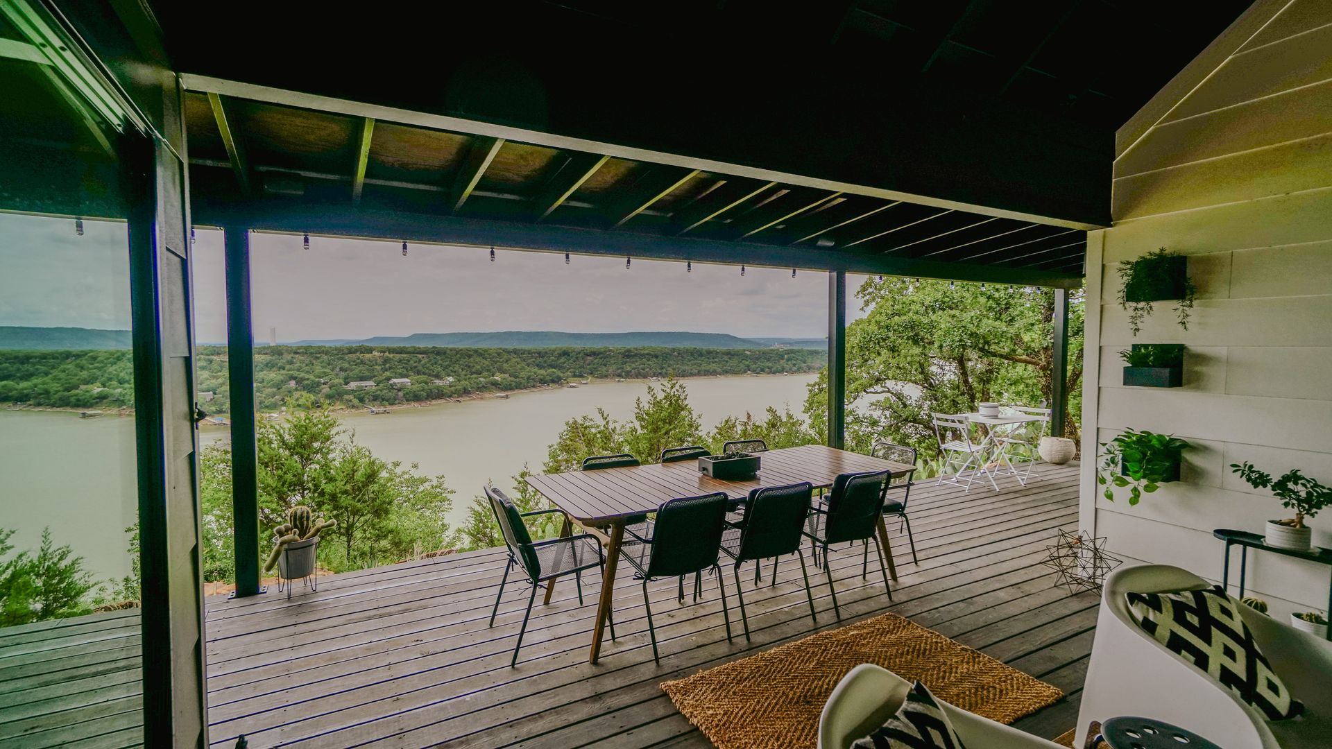 Covered patio with dining table, overlooking a lake and trees.