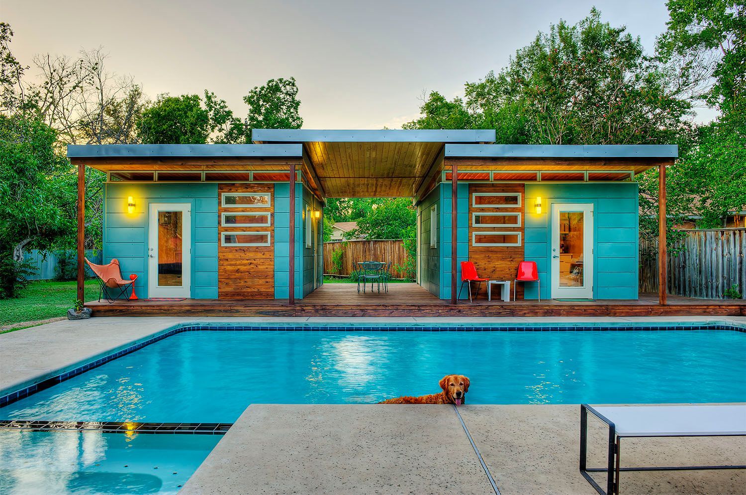 A blue house with a swimming pool in front of it