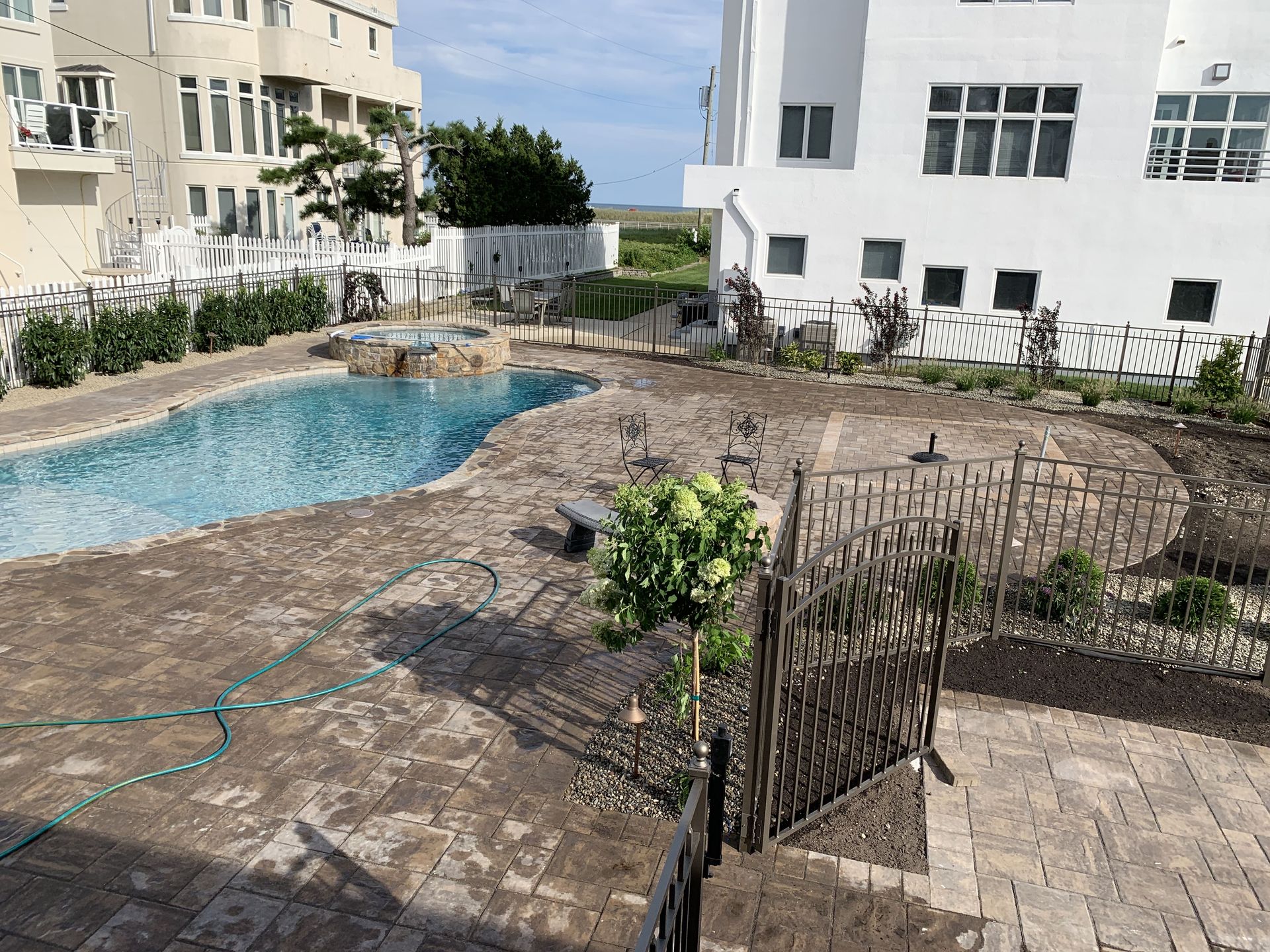 Courtyard with a small blue pool beside white apartment buildings and a fenced patio area