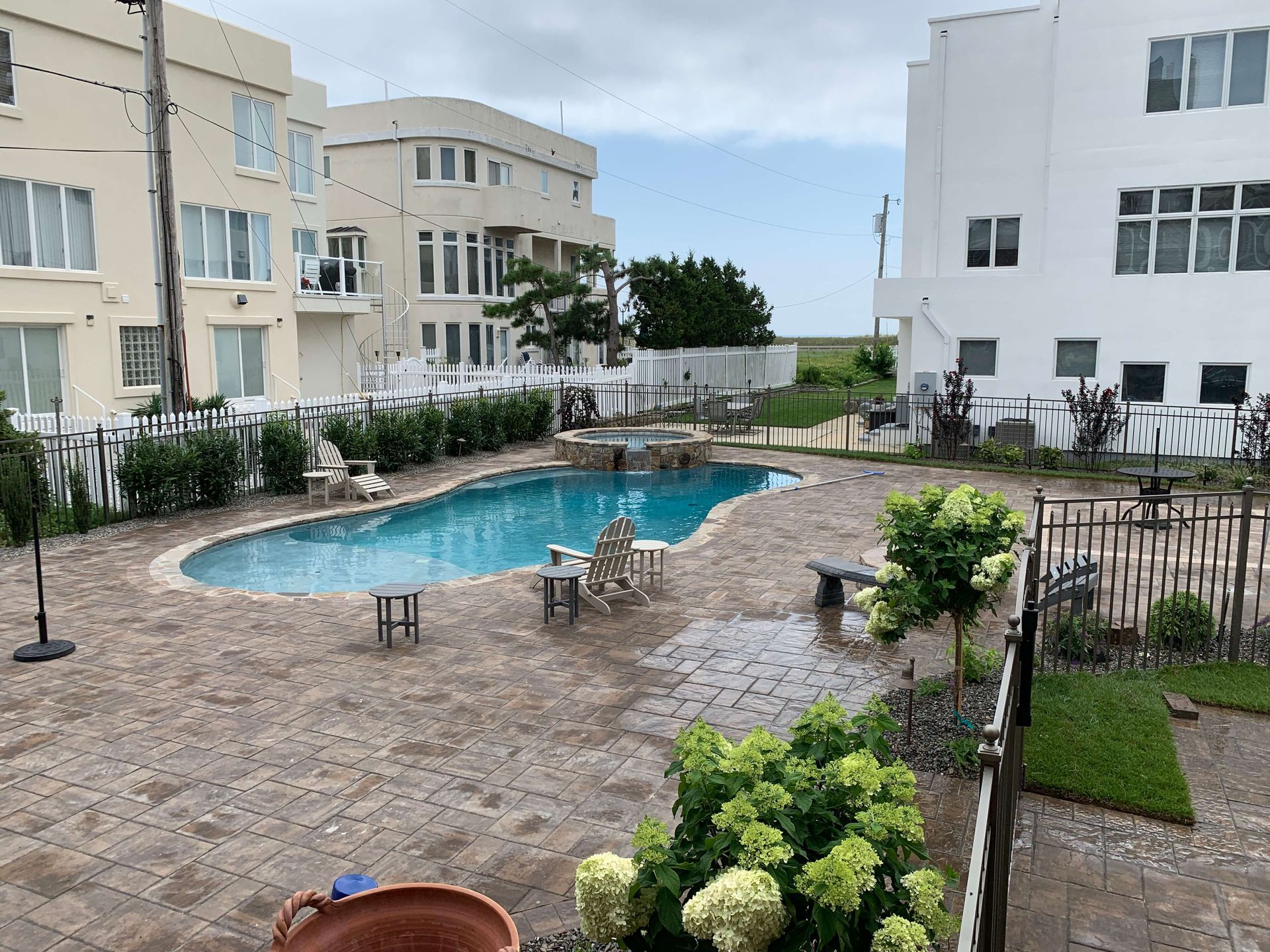 Courtyard with a small blue swimming pool, wet stone paving, lounge chairs, and apartment buildings around it