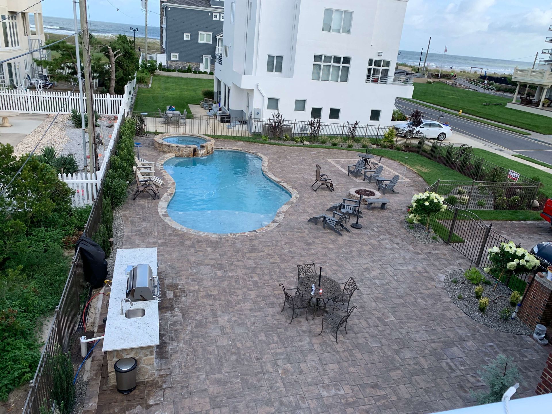 Courtyard pool with lounge chairs beside white apartment buildings and a paved patio