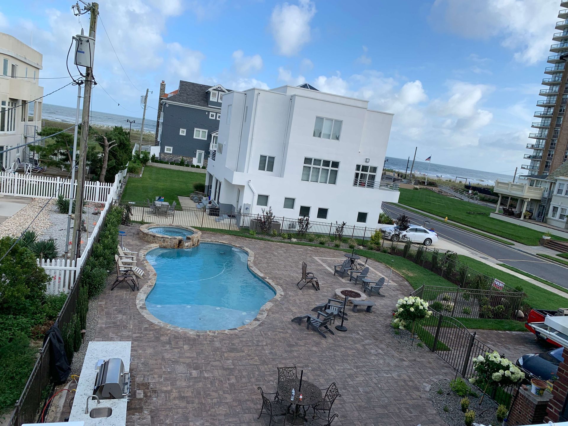 Courtyard with small blue pool, patio tables, and white buildings under a cloudy sky