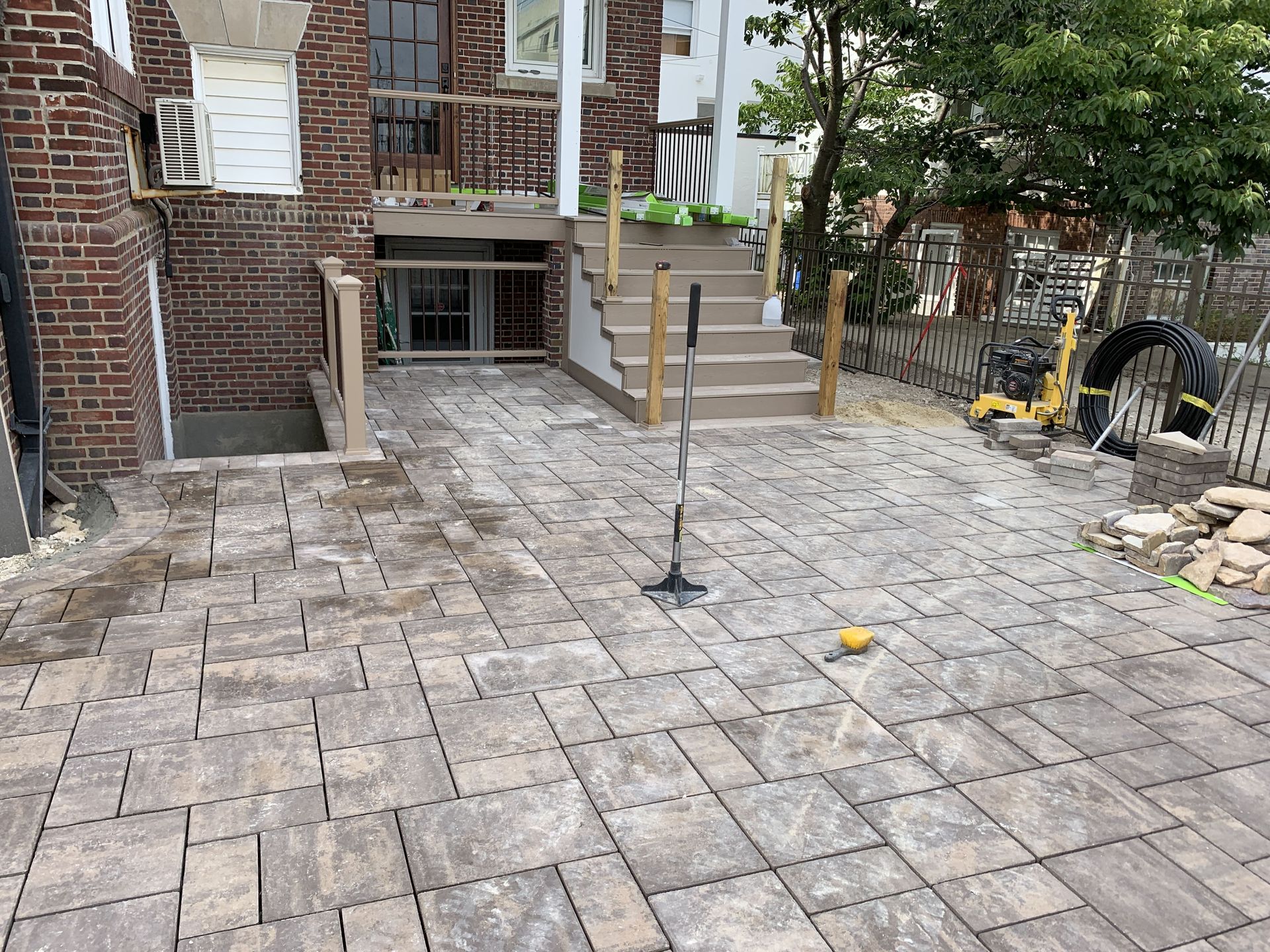 Brick patio with a small tree and steps leading to a building entrance.