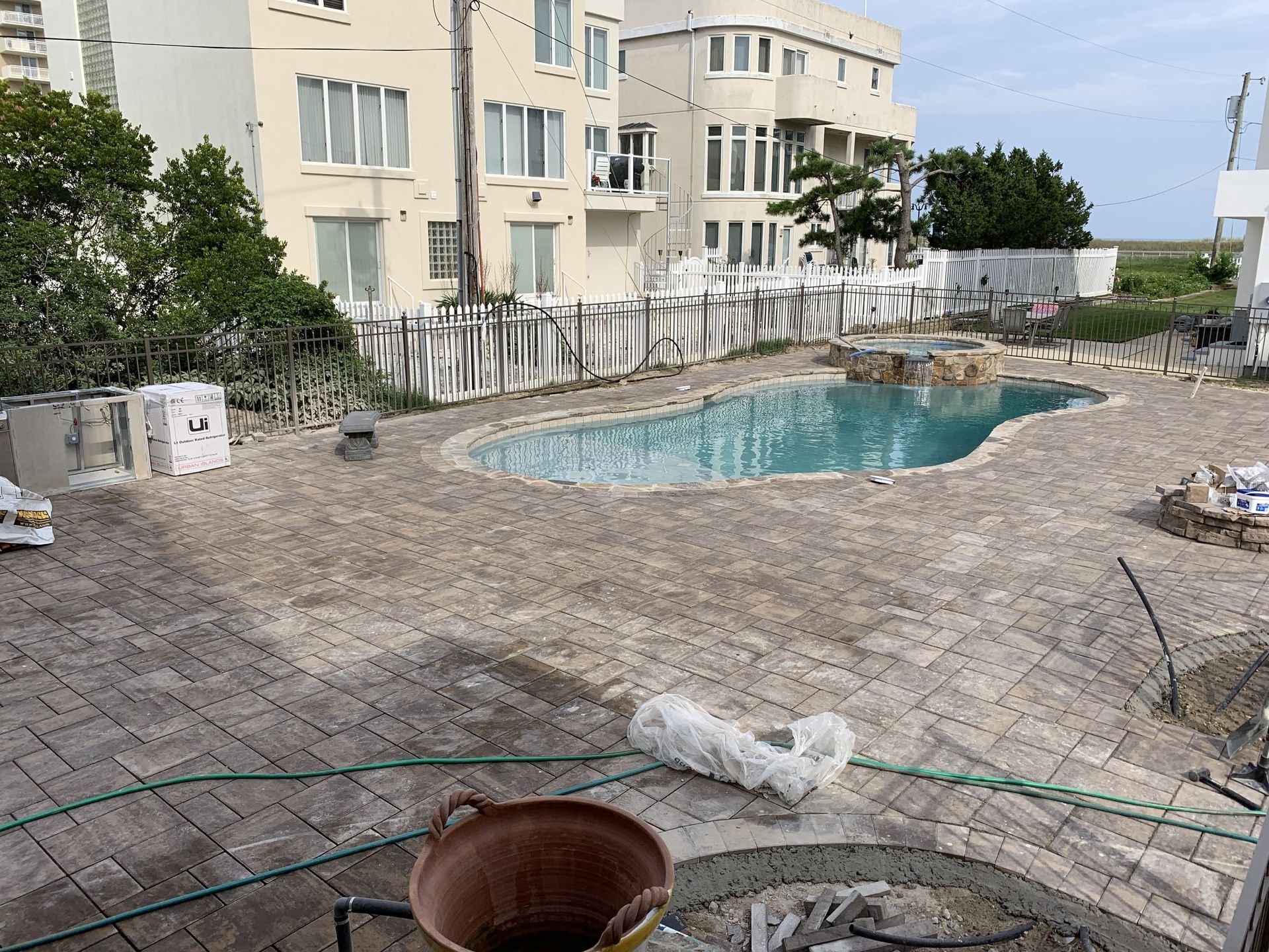 Courtyard with a small turquoise pool beside apartment buildings and trees, seen from a paved patio