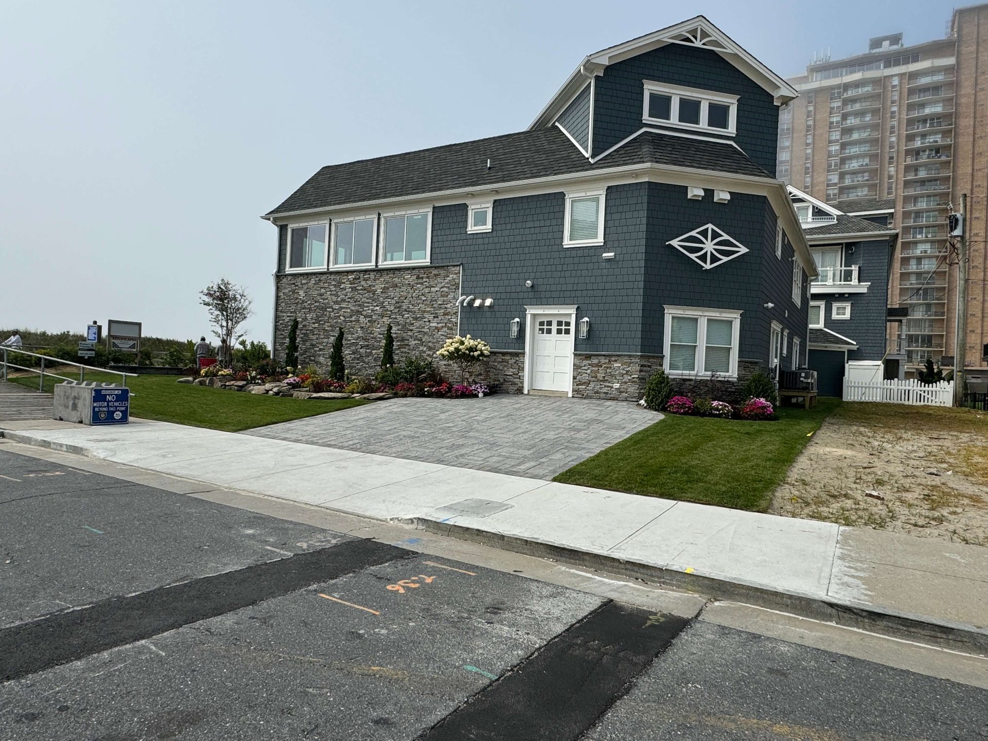 Two-story gray house with stone accents and a front lawn on a suburban street
