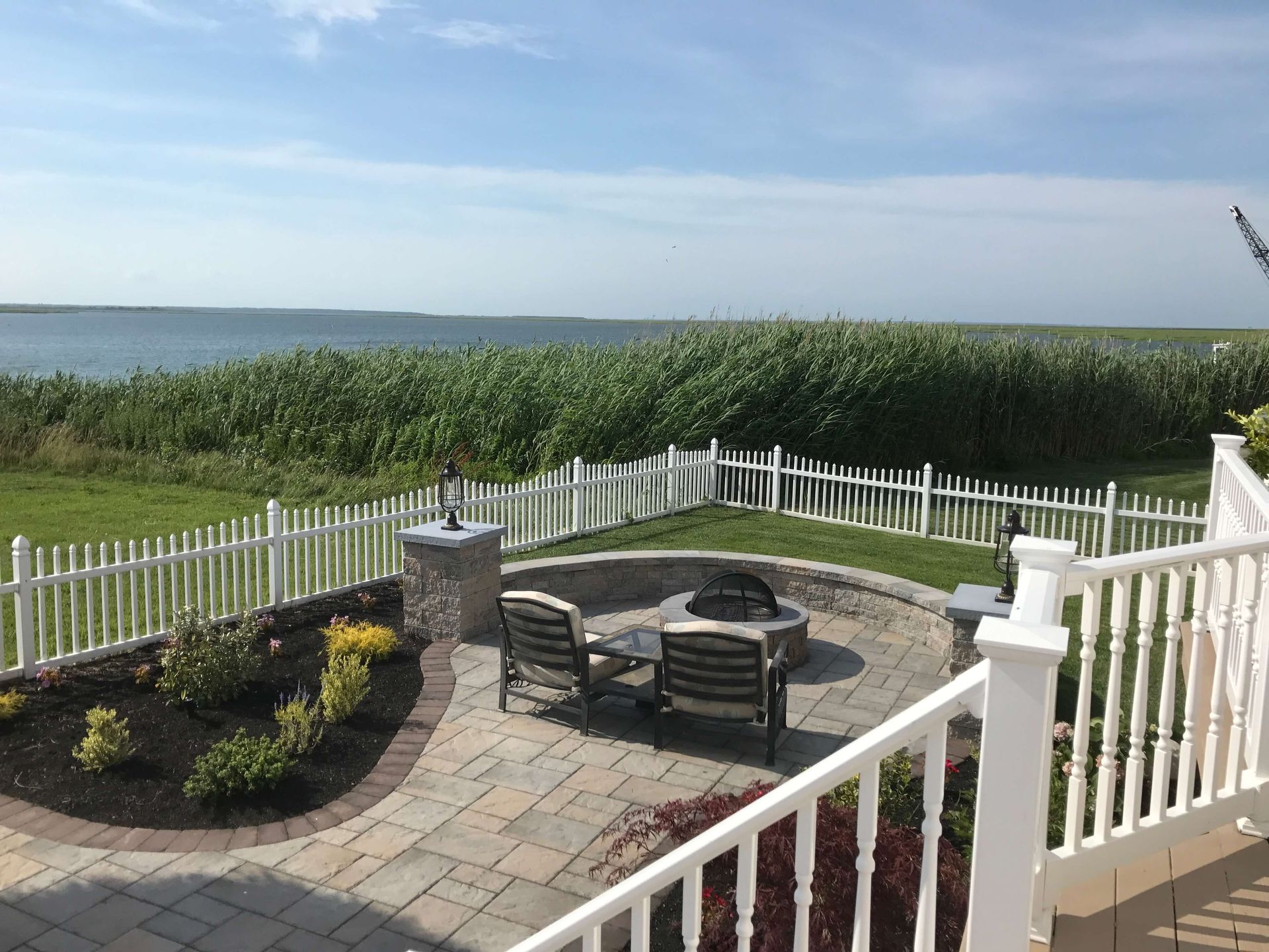 Patio with fire pit and chairs overlooking the ocean and tall green grasses