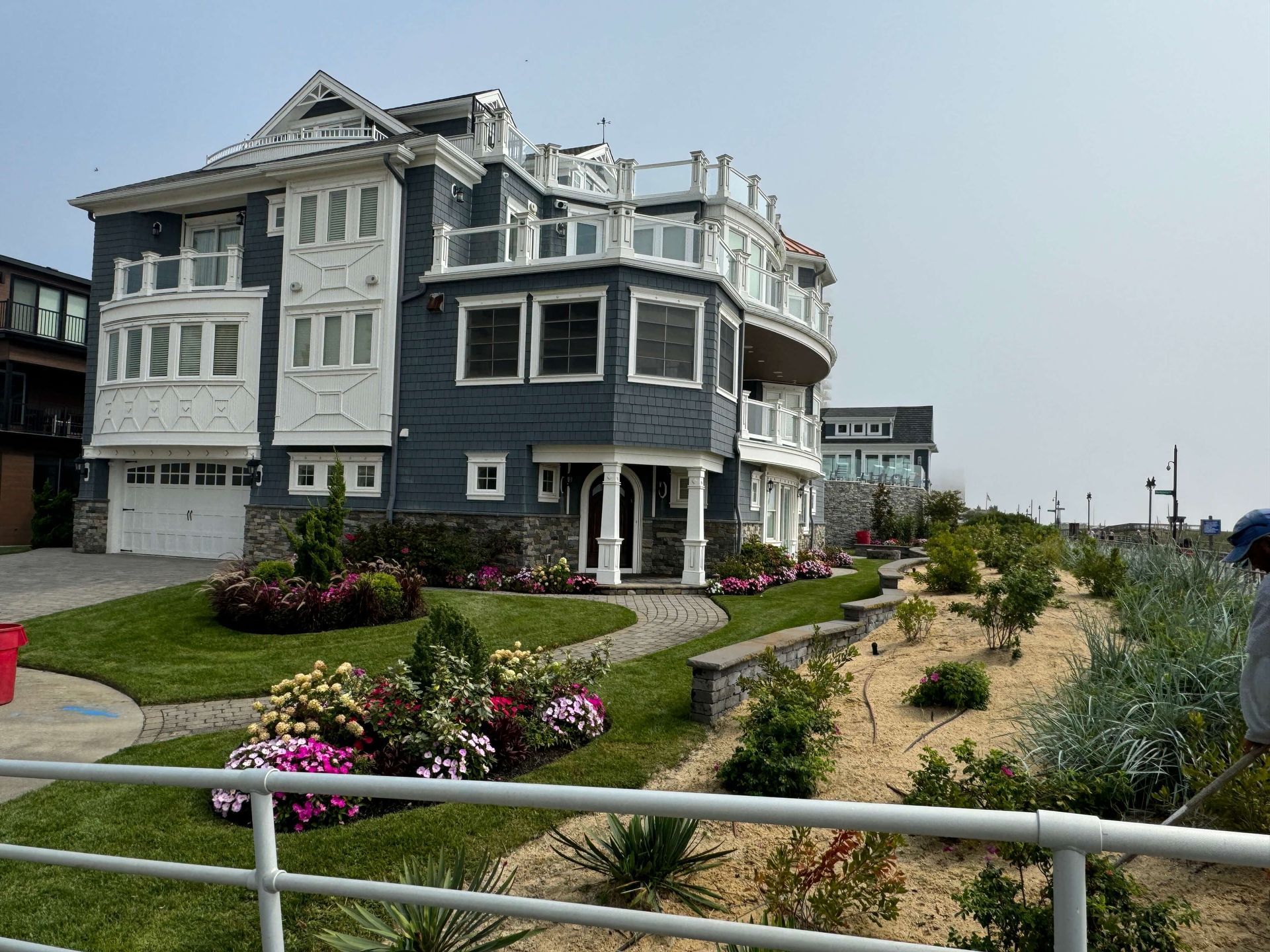 Coastal seaside house with dark gray siding, white trim, landscaped garden, and ocean view