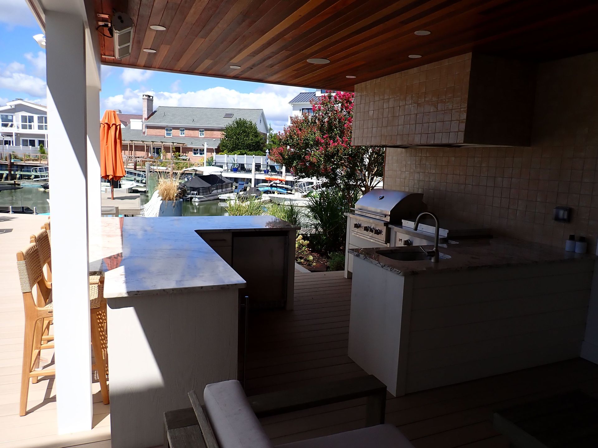 Covered marina patio with white counters, grill, and view of boats and water beyond.