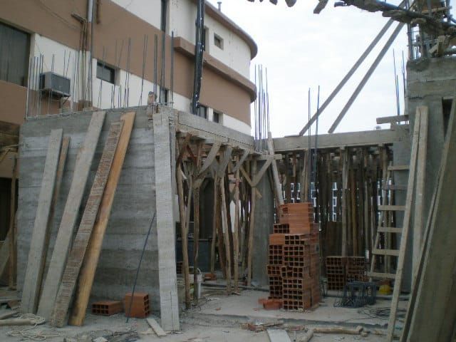 Obra en construcción con soportes de madera y andamios junto a la pared de un edificio.