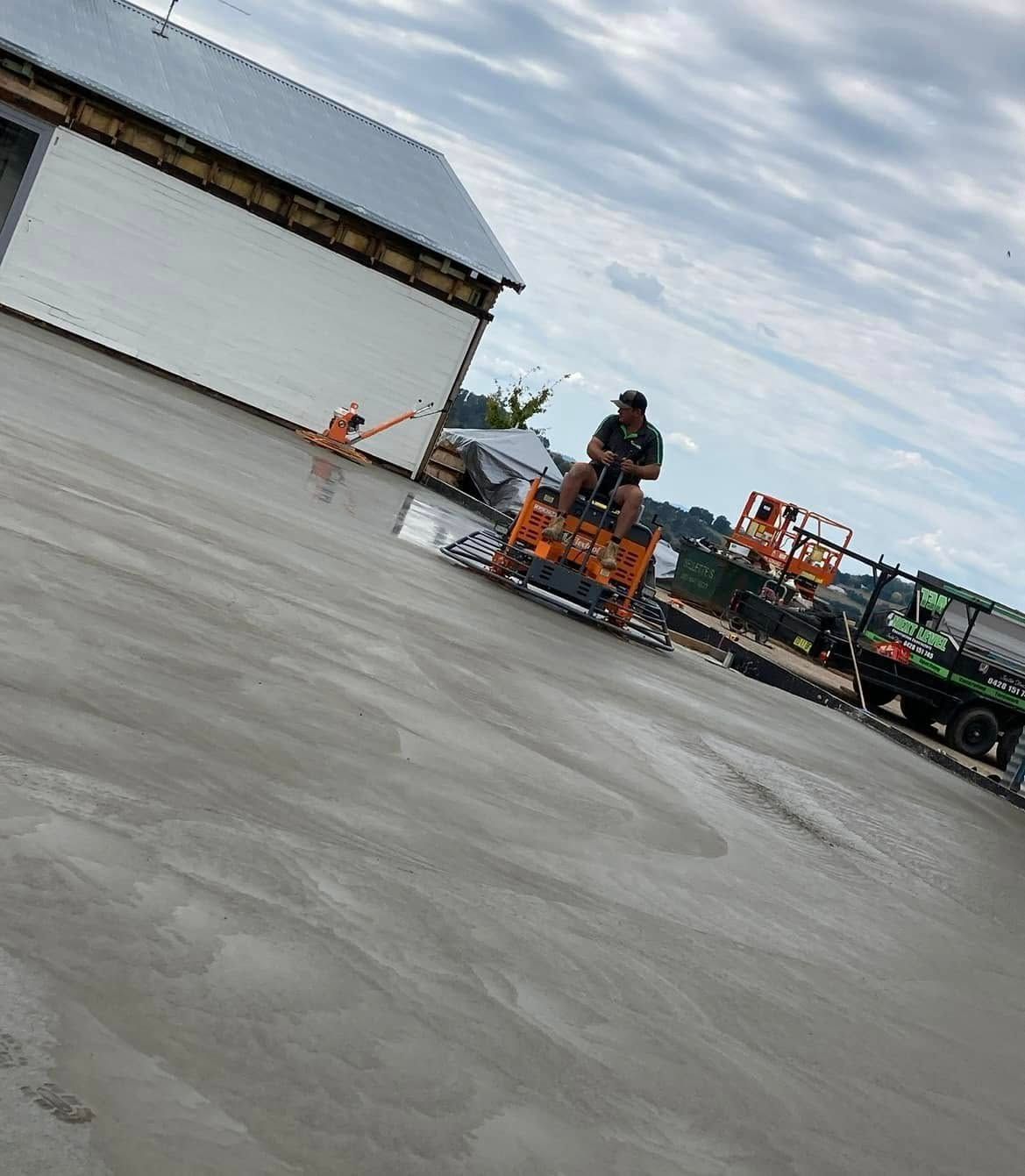 A Man is Riding a Machine on a Concrete Floor — Next Level Construction Contractors in Gundagai, NSW