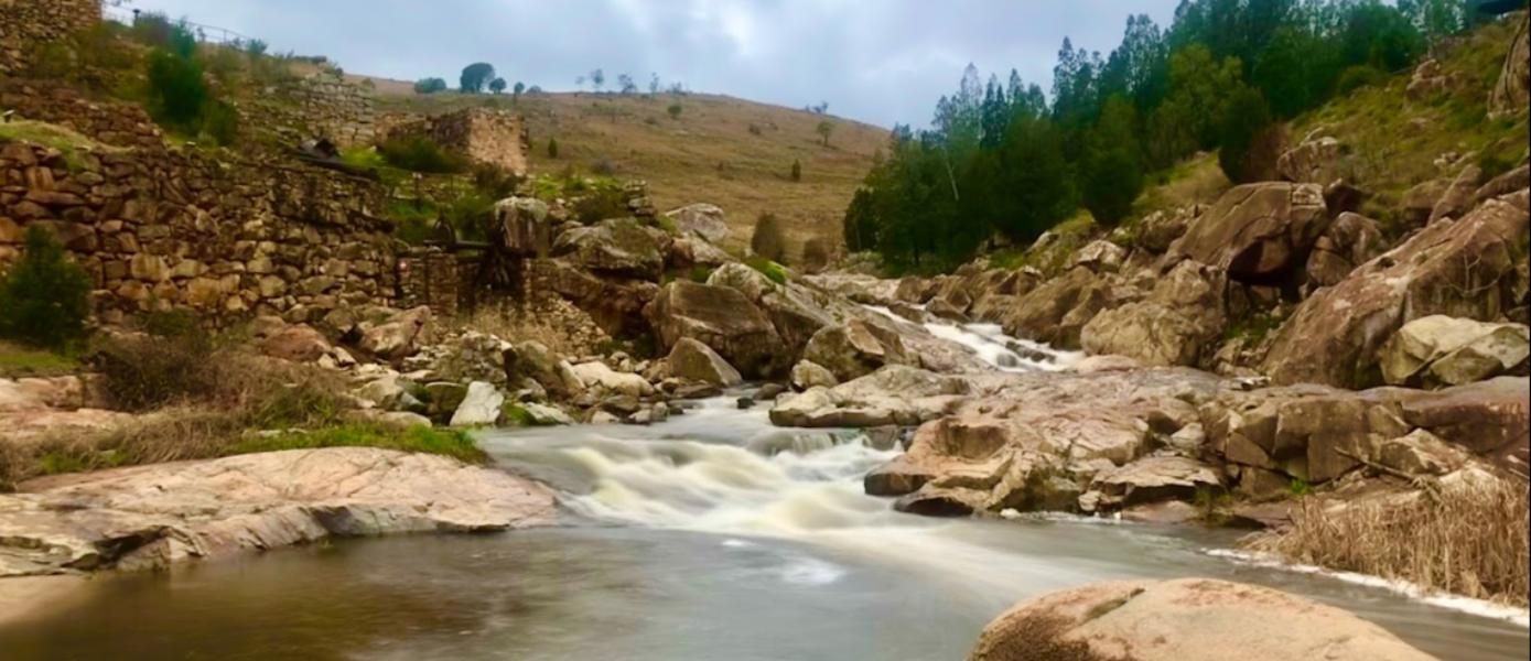 A River Flowing Through a Valley Surrounded by Rocks and Trees — Next Level Construction Contractors in Adelong, NSW